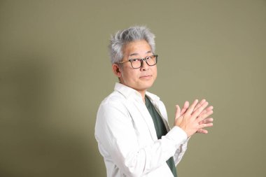 Doğu Asyalı bir işadamının yarım vücut portresi. Koyu yeşil bir arka planda izole edilmiş. Stüdyoda çekilmiş..