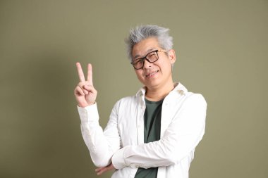 Doğu Asyalı bir işadamının yarım vücut portresi. Koyu yeşil bir arka planda izole edilmiş. Stüdyoda çekilmiş..