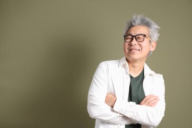 Doğu Asyalı bir işadamının yarım vücut portresi. Koyu yeşil bir arka planda izole edilmiş. Stüdyoda çekilmiş..