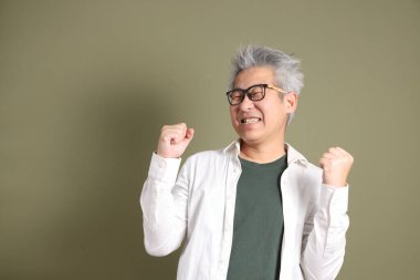 Doğu Asyalı bir işadamının yarım vücut portresi. Koyu yeşil bir arka planda izole edilmiş. Stüdyoda çekilmiş..