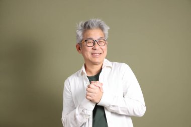 Doğu Asyalı bir işadamının yarım vücut portresi. Koyu yeşil bir arka planda izole edilmiş. Stüdyoda çekilmiş..