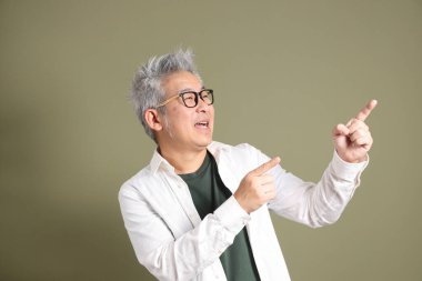 Doğu Asyalı bir işadamının yarım vücut portresi. Koyu yeşil bir arka planda izole edilmiş. Stüdyoda çekilmiş..