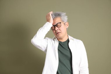 Doğu Asyalı bir işadamının yarım vücut portresi. Koyu yeşil bir arka planda izole edilmiş. Stüdyoda çekilmiş..