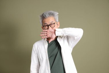 Doğu Asyalı bir işadamının yarım vücut portresi. Koyu yeşil bir arka planda izole edilmiş. Stüdyoda çekilmiş..