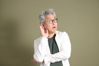 Doğu Asyalı bir işadamının yarım vücut portresi. Koyu yeşil bir arka planda izole edilmiş. Stüdyoda çekilmiş..