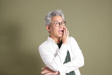 Doğu Asyalı bir işadamının yarım vücut portresi. Koyu yeşil bir arka planda izole edilmiş. Stüdyoda çekilmiş..