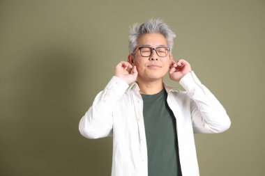 Doğu Asyalı bir işadamının yarım vücut portresi. Koyu yeşil bir arka planda izole edilmiş. Stüdyoda çekilmiş..