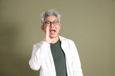 Doğu Asyalı bir işadamının yarım vücut portresi. Koyu yeşil bir arka planda izole edilmiş. Stüdyoda çekilmiş..