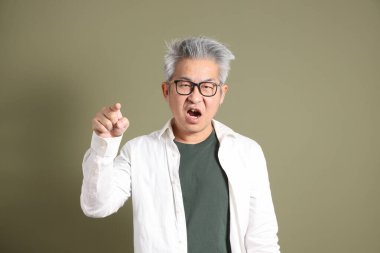 Doğu Asyalı bir işadamının yarım vücut portresi. Koyu yeşil bir arka planda izole edilmiş. Stüdyoda çekilmiş..