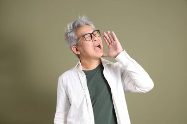 Doğu Asyalı bir işadamının yarım vücut portresi. Koyu yeşil bir arka planda izole edilmiş. Stüdyoda çekilmiş..