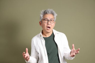 Doğu Asyalı bir işadamının yarım vücut portresi. Koyu yeşil bir arka planda izole edilmiş. Stüdyoda çekilmiş..