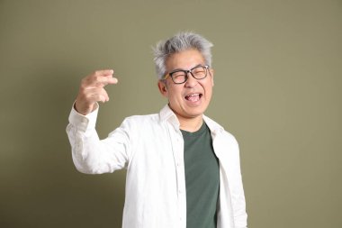 Doğu Asyalı bir işadamının yarım vücut portresi. Koyu yeşil bir arka planda izole edilmiş. Stüdyoda çekilmiş..