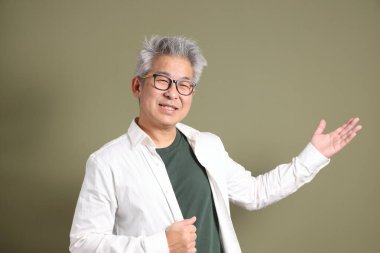 Doğu Asyalı bir işadamının yarım vücut portresi. Koyu yeşil bir arka planda izole edilmiş. Stüdyoda çekilmiş..