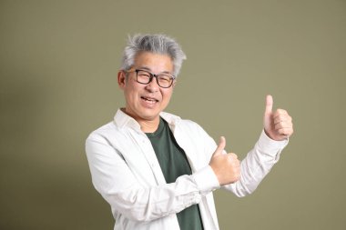 Doğu Asyalı bir işadamının yarım vücut portresi. Koyu yeşil bir arka planda izole edilmiş. Stüdyoda çekilmiş..