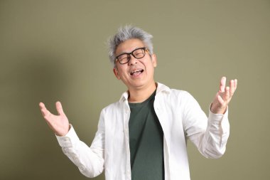 Doğu Asyalı bir işadamının yarım vücut portresi. Koyu yeşil bir arka planda izole edilmiş. Stüdyoda çekilmiş..