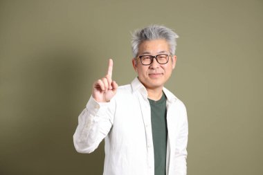 Doğu Asyalı bir işadamının yarım vücut portresi. Koyu yeşil bir arka planda izole edilmiş. Stüdyoda çekilmiş..