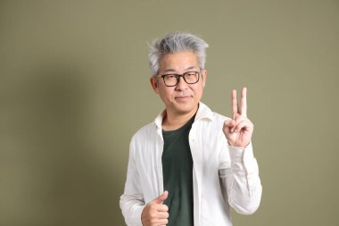 Doğu Asyalı bir işadamının yarım vücut portresi. Koyu yeşil bir arka planda izole edilmiş. Stüdyoda çekilmiş..