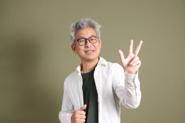 Doğu Asyalı bir işadamının yarım vücut portresi. Koyu yeşil bir arka planda izole edilmiş. Stüdyoda çekilmiş..