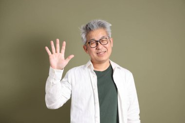 Doğu Asyalı bir işadamının yarım vücut portresi. Koyu yeşil bir arka planda izole edilmiş. Stüdyoda çekilmiş..