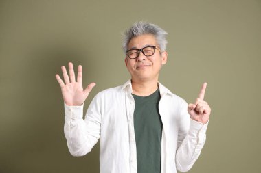 Doğu Asyalı bir işadamının yarım vücut portresi. Koyu yeşil bir arka planda izole edilmiş. Stüdyoda çekilmiş..