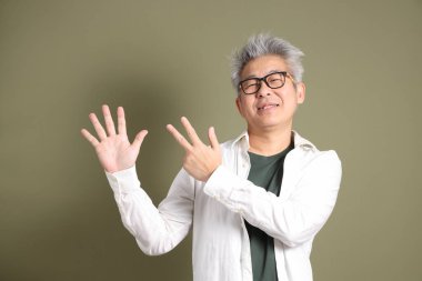 Doğu Asyalı bir işadamının yarım vücut portresi. Koyu yeşil bir arka planda izole edilmiş. Stüdyoda çekilmiş..