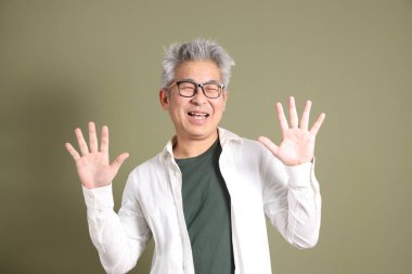 Doğu Asyalı bir işadamının yarım vücut portresi. Koyu yeşil bir arka planda izole edilmiş. Stüdyoda çekilmiş..