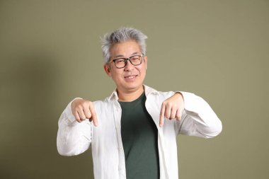 Doğu Asyalı bir işadamının yarım vücut portresi. Koyu yeşil bir arka planda izole edilmiş. Stüdyoda çekilmiş..