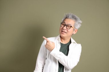 Doğu Asyalı bir işadamının yarım vücut portresi. Koyu yeşil bir arka planda izole edilmiş. Stüdyoda çekilmiş..