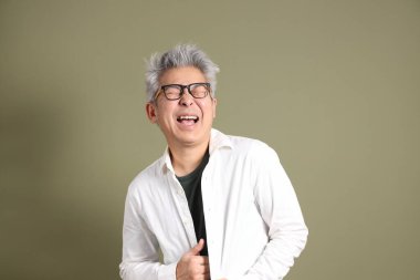 Doğu Asyalı bir işadamının yarım vücut portresi. Koyu yeşil bir arka planda izole edilmiş. Stüdyoda çekilmiş..