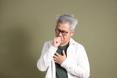 Doğu Asyalı bir işadamının yarım vücut portresi. Koyu yeşil bir arka planda izole edilmiş. Stüdyoda çekilmiş..