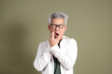 Doğu Asyalı bir işadamının yarım vücut portresi. Koyu yeşil bir arka planda izole edilmiş. Stüdyoda çekilmiş..