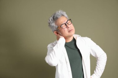 Doğu Asyalı bir işadamının yarım vücut portresi. Koyu yeşil bir arka planda izole edilmiş. Stüdyoda çekilmiş..