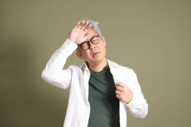 Doğu Asyalı bir işadamının yarım vücut portresi. Koyu yeşil bir arka planda izole edilmiş. Stüdyoda çekilmiş..