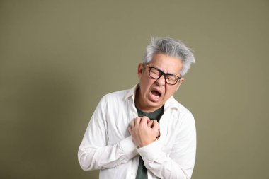 Doğu Asyalı bir işadamının yarım vücut portresi. Koyu yeşil bir arka planda izole edilmiş. Stüdyoda çekilmiş..