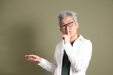 Doğu Asyalı bir işadamının yarım vücut portresi. Koyu yeşil bir arka planda izole edilmiş. Stüdyoda çekilmiş..