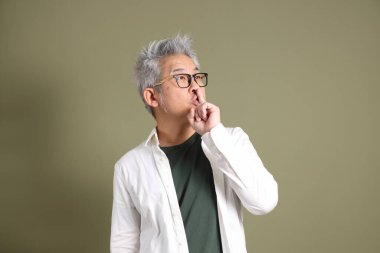 Doğu Asyalı bir işadamının yarım vücut portresi. Koyu yeşil bir arka planda izole edilmiş. Stüdyoda çekilmiş..