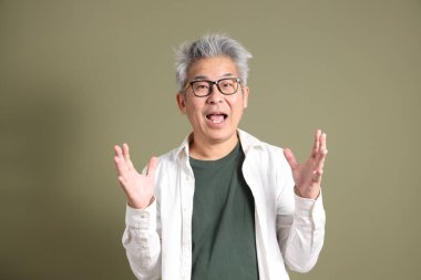 Doğu Asyalı bir işadamının yarım vücut portresi. Koyu yeşil bir arka planda izole edilmiş. Stüdyoda çekilmiş..