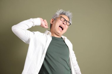 Doğu Asyalı bir işadamının yarım vücut portresi. Koyu yeşil bir arka planda izole edilmiş. Stüdyoda çekilmiş..