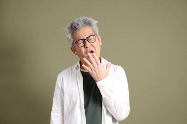 Doğu Asyalı bir işadamının yarım vücut portresi. Koyu yeşil bir arka planda izole edilmiş. Stüdyoda çekilmiş..