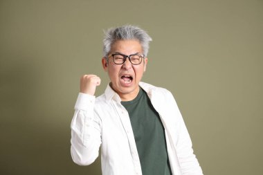 Doğu Asyalı bir işadamının yarım vücut portresi. Koyu yeşil bir arka planda izole edilmiş. Stüdyoda çekilmiş..