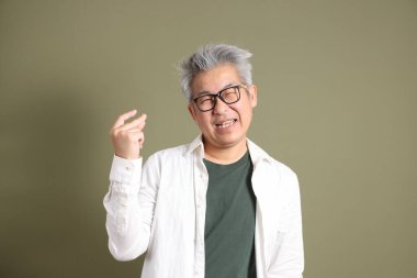 Doğu Asyalı bir işadamının yarım vücut portresi. Koyu yeşil bir arka planda izole edilmiş. Stüdyoda çekilmiş..