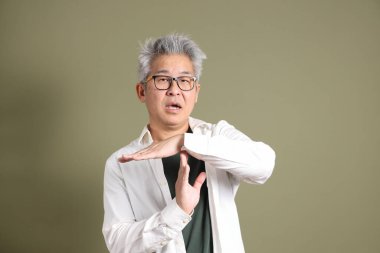 Doğu Asyalı bir işadamının yarım vücut portresi. Koyu yeşil bir arka planda izole edilmiş. Stüdyoda çekilmiş..