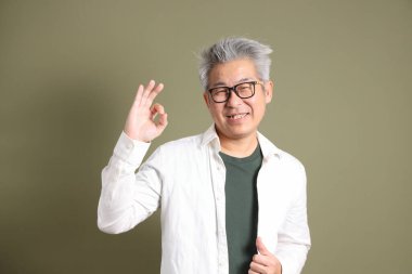 Doğu Asyalı bir işadamının yarım vücut portresi. Koyu yeşil bir arka planda izole edilmiş. Stüdyoda çekilmiş..