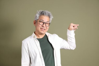 Doğu Asyalı bir işadamının yarım vücut portresi. Koyu yeşil bir arka planda izole edilmiş. Stüdyoda çekilmiş..