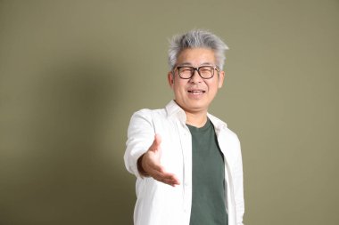 Doğu Asyalı bir işadamının yarım vücut portresi. Koyu yeşil bir arka planda izole edilmiş. Stüdyoda çekilmiş..