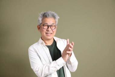 Doğu Asyalı bir işadamının yarım vücut portresi. Koyu yeşil bir arka planda izole edilmiş. Stüdyoda çekilmiş..