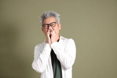 Doğu Asyalı bir işadamının yarım vücut portresi. Koyu yeşil bir arka planda izole edilmiş. Stüdyoda çekilmiş..