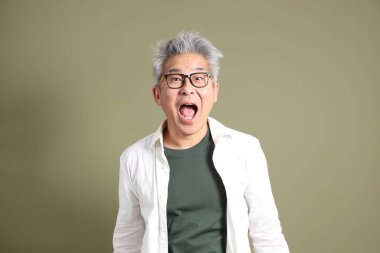 Doğu Asyalı bir işadamının yarım vücut portresi. Koyu yeşil bir arka planda izole edilmiş. Stüdyoda çekilmiş..