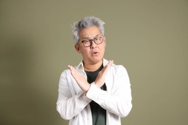 Doğu Asyalı bir işadamının yarım vücut portresi. Koyu yeşil bir arka planda izole edilmiş. Stüdyoda çekilmiş..