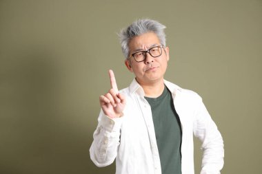 Doğu Asyalı bir işadamının yarım vücut portresi. Koyu yeşil bir arka planda izole edilmiş. Stüdyoda çekilmiş..